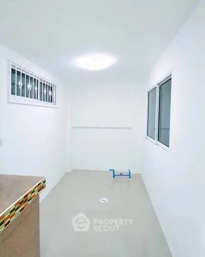Bright utility room with tiled floor and window, ideal for laundry or storage use.