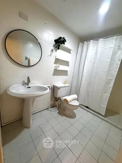 Modern bathroom with round mirror, pedestal sink, and shower curtain in a bright, tiled space.