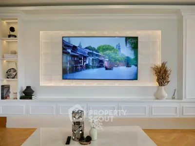 Elegant living room with modern decor and wall-mounted TV, featuring stylish shelving and decorative accents.