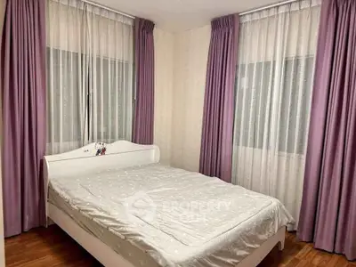 Cozy bedroom with elegant purple curtains and a comfortable bed, perfect for relaxation.