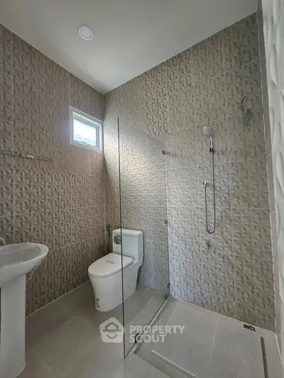 Modern bathroom with textured tiles and glass shower enclosure
