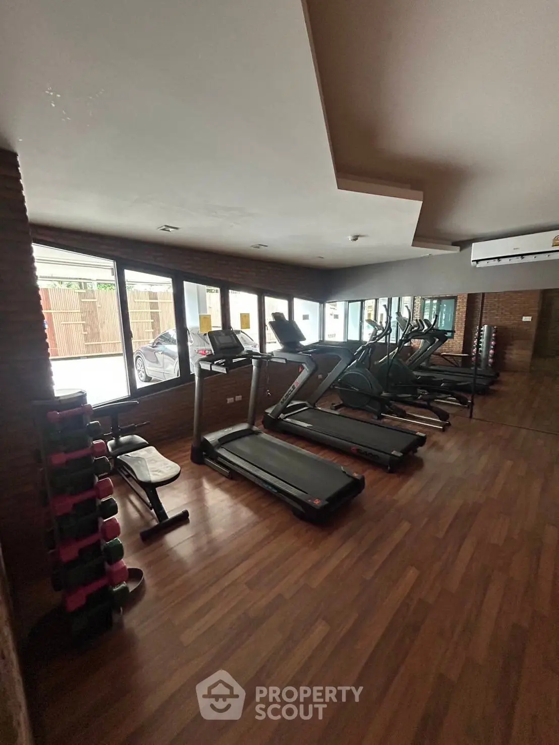 Spacious gym with modern equipment and large windows in a residential building.