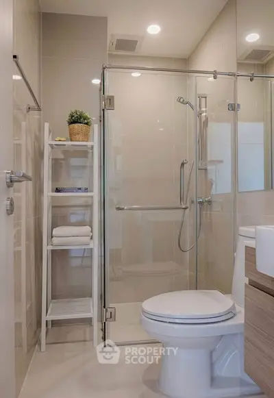 Modern bathroom with glass shower and sleek fixtures in contemporary apartment.