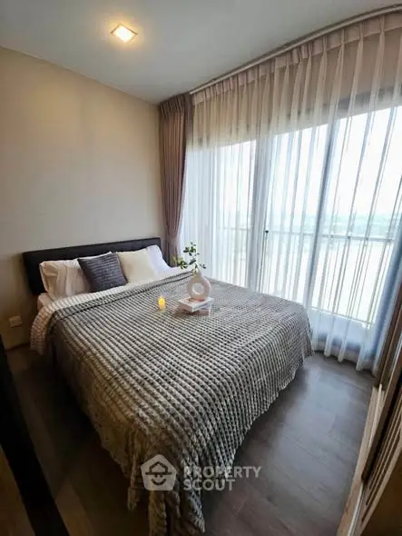 Cozy bedroom with large window and elegant curtains, featuring a comfortable bed and stylish decor.