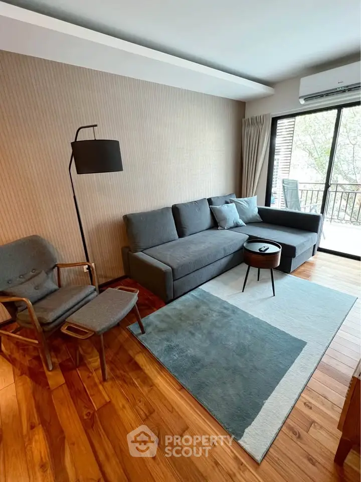 Modern living room with stylish furniture and large window overlooking balcony.
