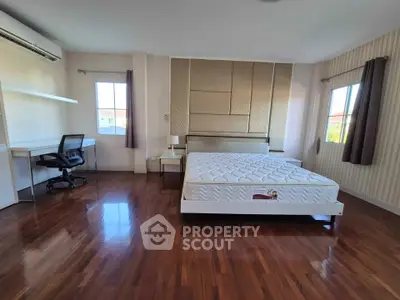 Spacious bedroom with hardwood floors and modern furnishings