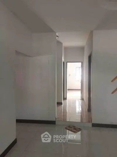 Spacious hallway in modern apartment with natural light and tiled flooring.