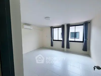 Spacious unfurnished room with large windows and air conditioning in modern apartment.