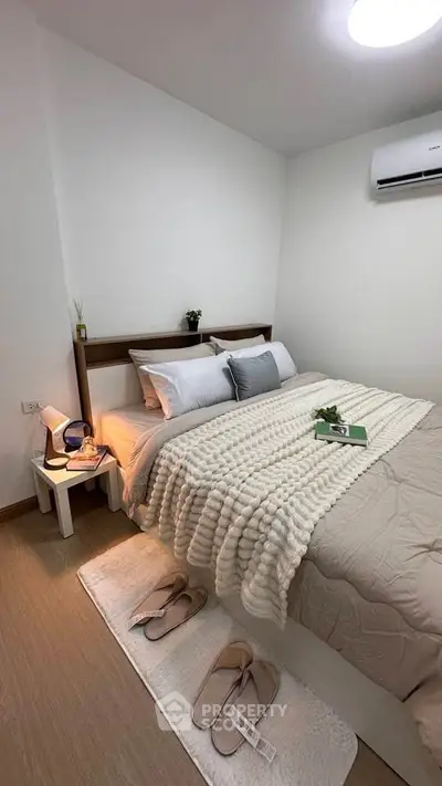Cozy bedroom with modern decor and air conditioning, featuring a comfortable bed and stylish lighting.