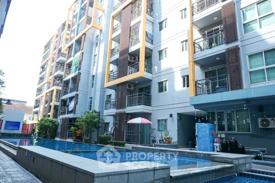 Modern apartment building with outdoor pool and balconies in urban setting.