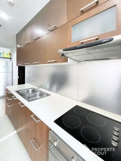 Modern kitchen with sleek cabinetry and electric cooktop in a stylish apartment.