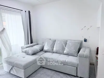 Modern living room with stylish gray sectional sofa and natural light from large window.