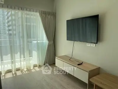 Modern living room with wall-mounted TV and large window for natural light.