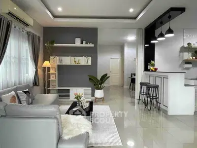 Modern living room with sleek design and open kitchen layout, featuring stylish furniture and decor.
