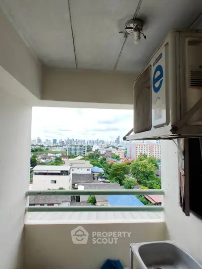 City view from a small balcony with air conditioning unit and sink.
