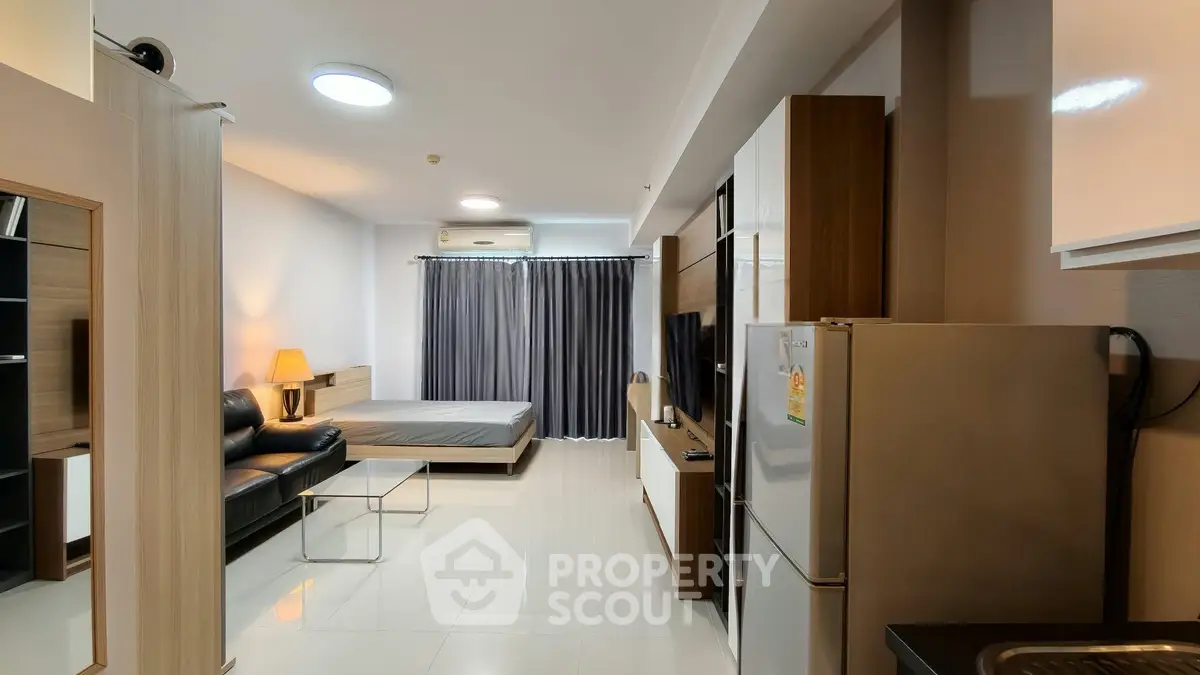 Modern studio apartment with open layout, featuring sleek kitchen and cozy living area.