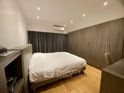 Spacious modern bedroom with wooden flooring and large wardrobe