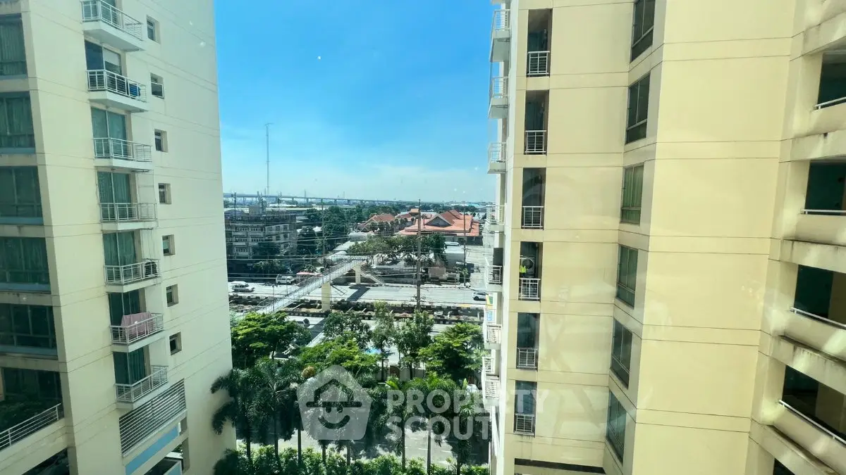 Stunning cityscape view from high-rise apartment with lush greenery and modern architecture.