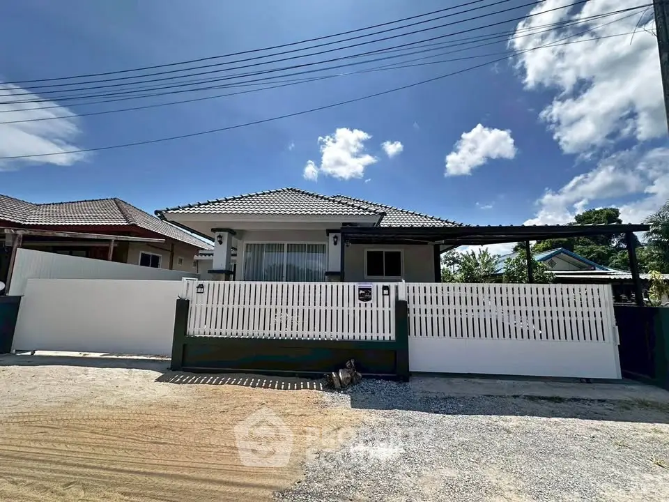 Charming single-story home with modern fence and spacious driveway under a clear blue sky.