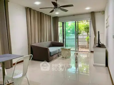 Spacious living room with modern decor and large windows overlooking greenery.