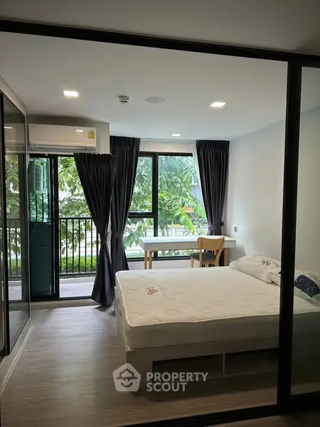 Modern bedroom with large window and garden view, featuring sleek design and natural light.