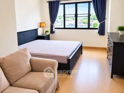 Spacious bedroom with modern furnishings and large window offering natural light and scenic views.