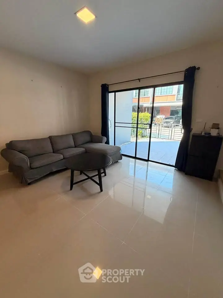 Spacious living room with modern sofa and large sliding glass doors leading to a balcony.