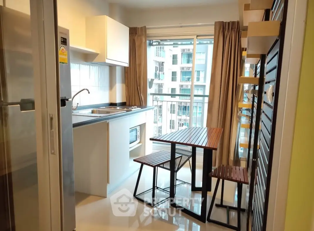 Modern kitchen with open layout and balcony view in urban apartment.