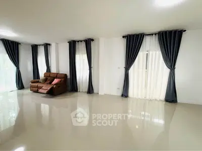Spacious living room with elegant curtains and a cozy sofa, perfect for relaxation and entertainment.