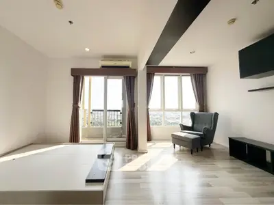 Spacious modern living room with large windows and city view, featuring elegant armchair and minimalist decor.