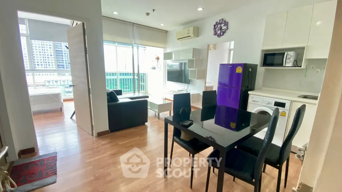 Modern open-plan living room with dining area, featuring sleek furniture and city views.