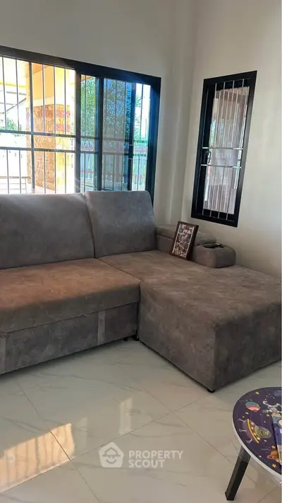 Modern living room with stylish gray sectional sofa and large windows offering natural light.