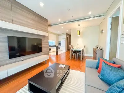 Modern living room with open layout, stylish furniture, and sleek kitchen in a contemporary apartment.