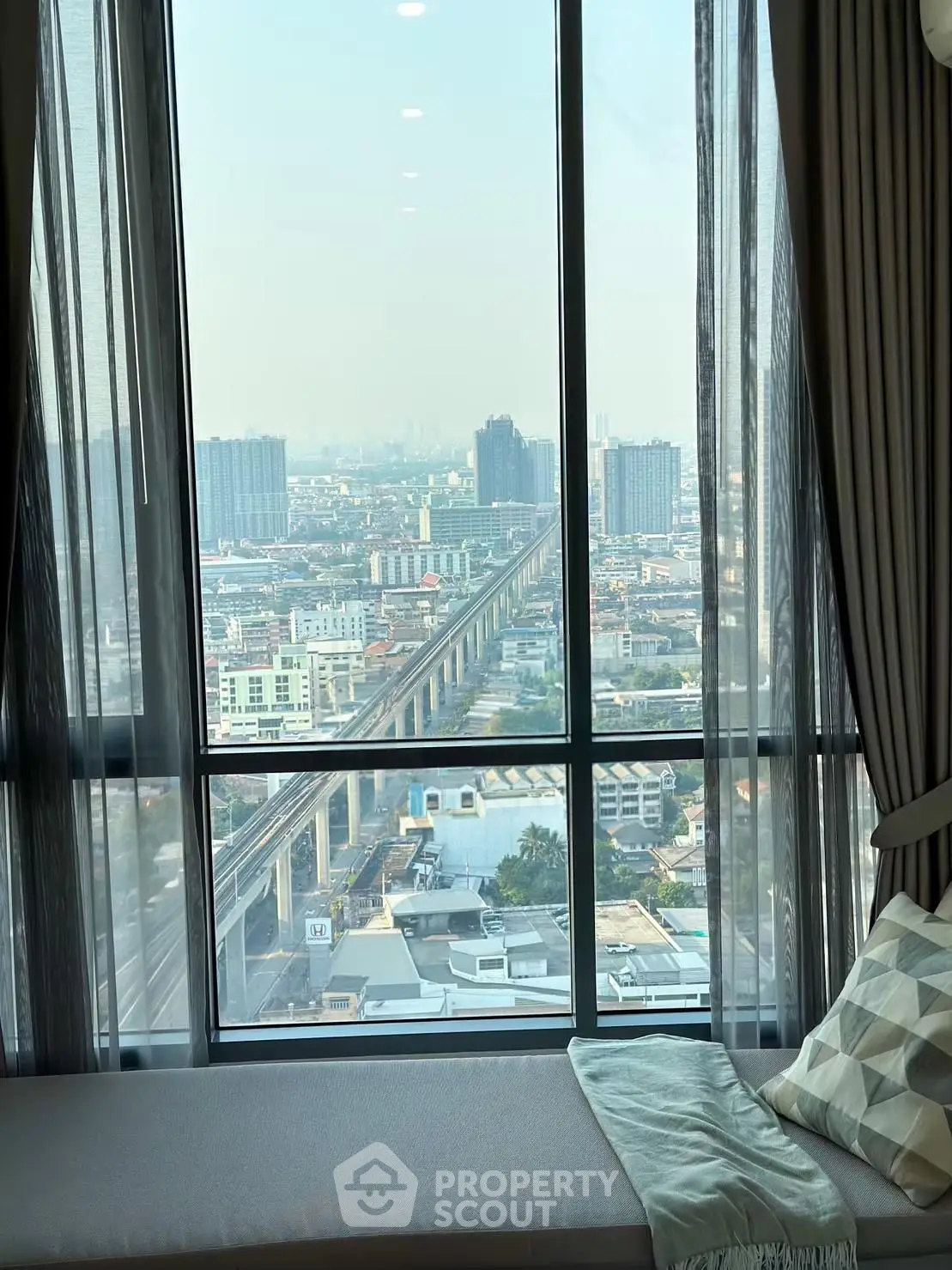 Stunning high-rise city view from a modern apartment window, showcasing urban skyline and transportation network.