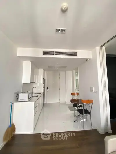Modern kitchen with sleek white cabinetry and compact dining area in a stylish apartment.