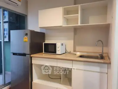 Modern kitchen with sleek cabinetry, stainless steel fridge, and microwave, perfect for urban living.