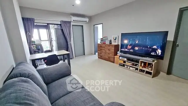 Spacious living room with modern decor and large TV, perfect for relaxation and entertainment.