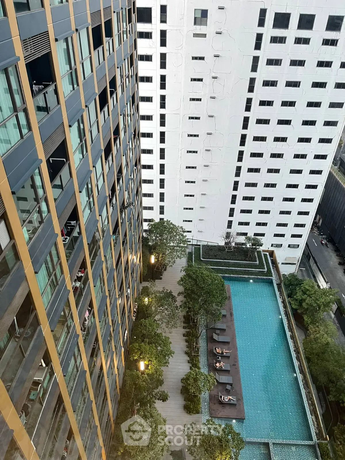 Stunning aerial view of modern apartment complex with luxurious pool and lush greenery.