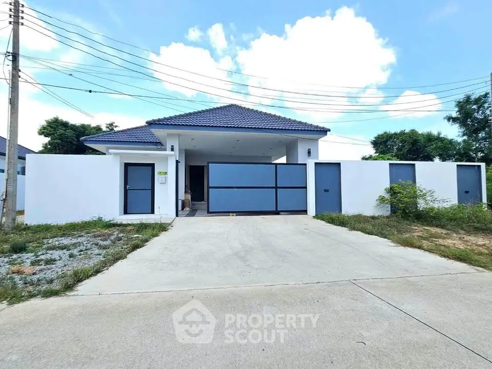 Modern single-story house with blue roof and gated driveway in a serene neighborhood.