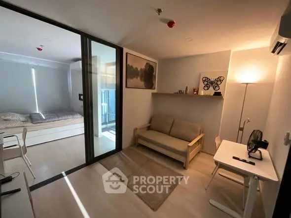 Modern studio apartment with cozy living area and bedroom, featuring sleek furniture and ambient lighting.