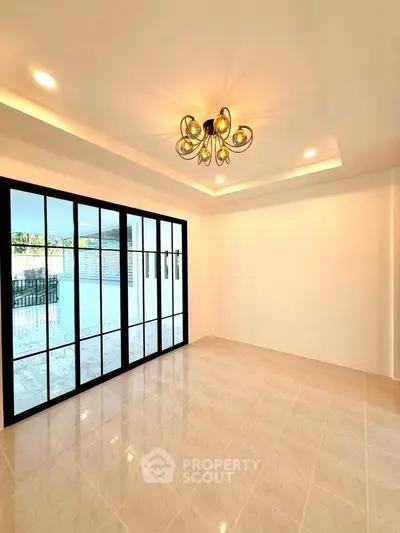 Spacious modern living room with elegant lighting and large glass doors opening to a patio.