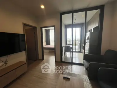 Modern apartment interior with open living room, kitchen, and bedroom view.