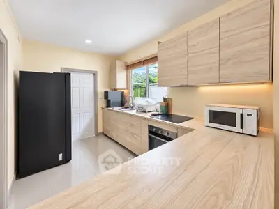 Modern kitchen with sleek wooden cabinets and built-in appliances, featuring a spacious countertop and natural light.
