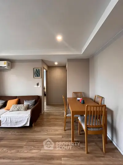 Modern living room with cozy sofa and dining area, featuring wooden flooring and stylish decor.