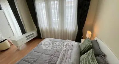 Cozy bedroom with stylish decor and natural light from large windows.