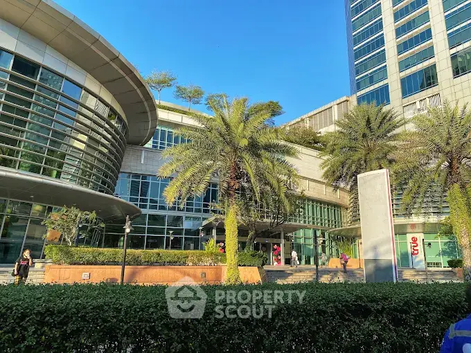 Modern commercial building exterior with lush landscaping and palm trees under a clear blue sky.