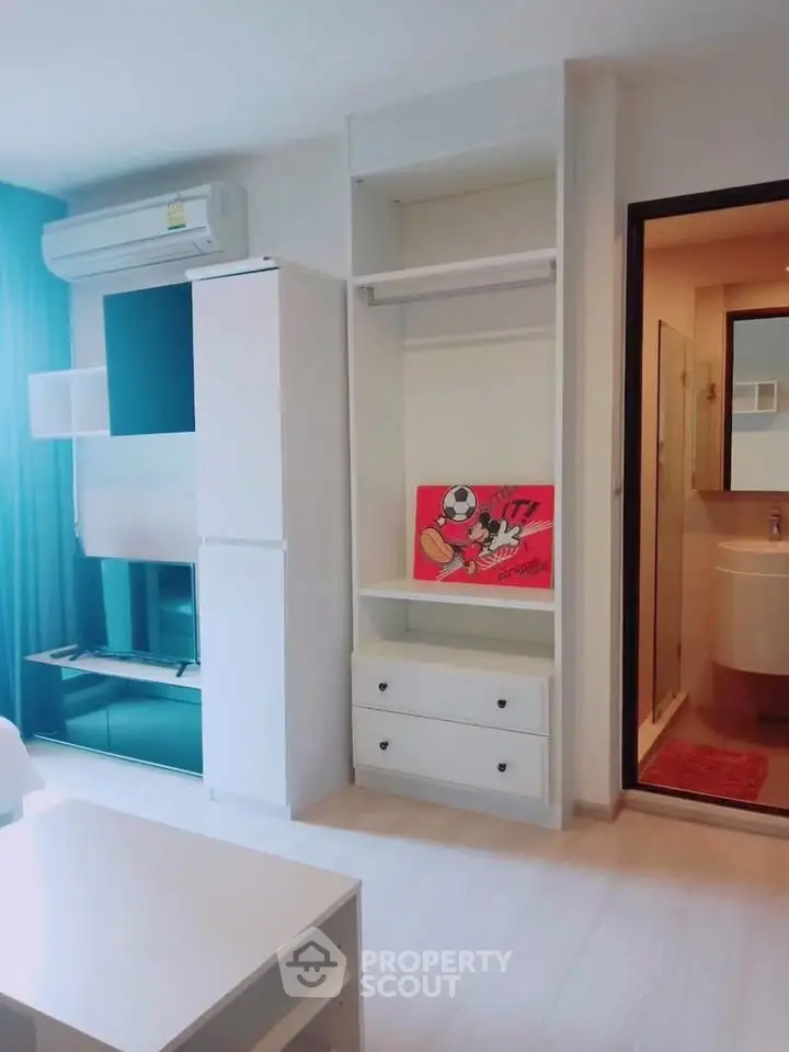 Modern living room with sleek storage and entertainment unit, adjacent to a compact bathroom.