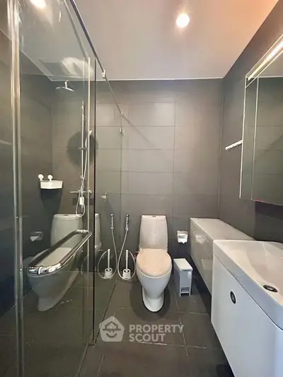 Modern bathroom with sleek fixtures and glass shower enclosure in a contemporary apartment.