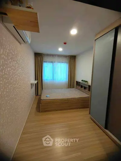 Cozy bedroom with modern design, featuring wooden flooring and ample natural light.