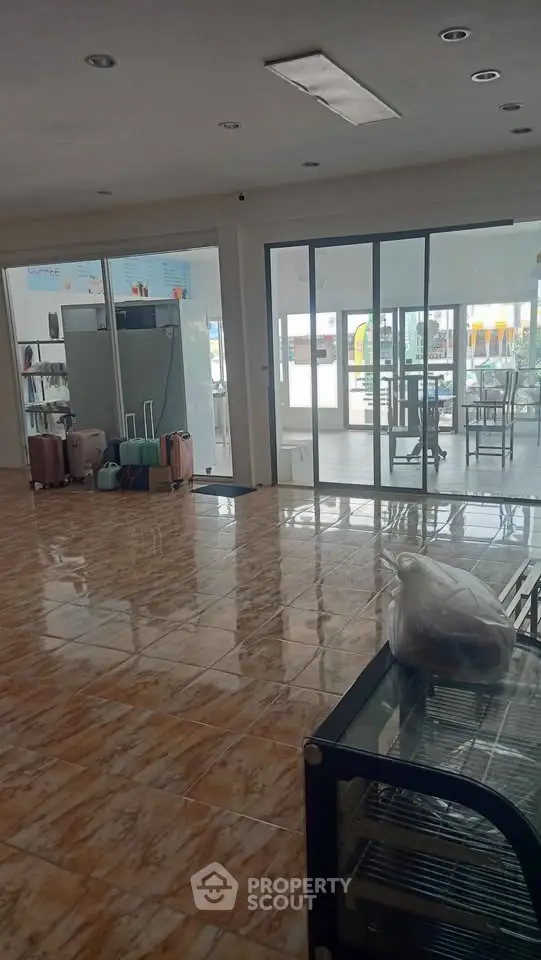 Spacious interior with tiled flooring and glass doors leading to a bright outdoor area, ideal for versatile use.